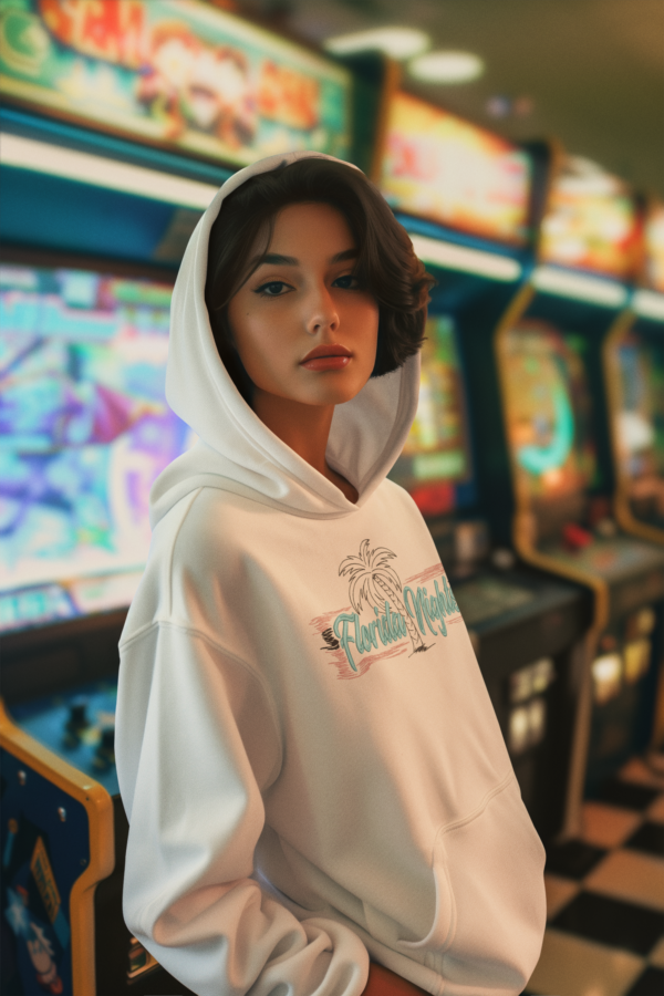 Woman in arcade wearing a Luxury white fleece hoodie with vibrant Miami-inspired embroidered lettering, combining premium fleece material with a sleek design, available in sizes S-3XL