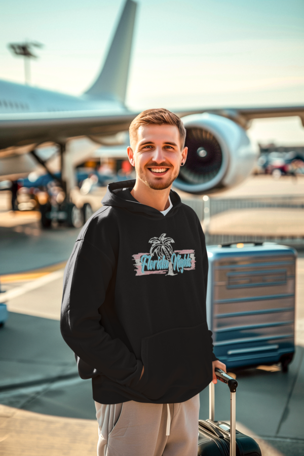 Smiling man in arcade wearing a Luxury black fleece hoodie with vibrant Miami-inspired embroidered lettering, combining premium fleece material with a sleek design, available in sizes S-3XL