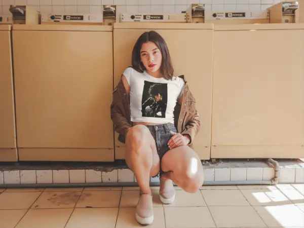 Woman kneeling in laundromat wearing a white - Prince Passion - Crop Top